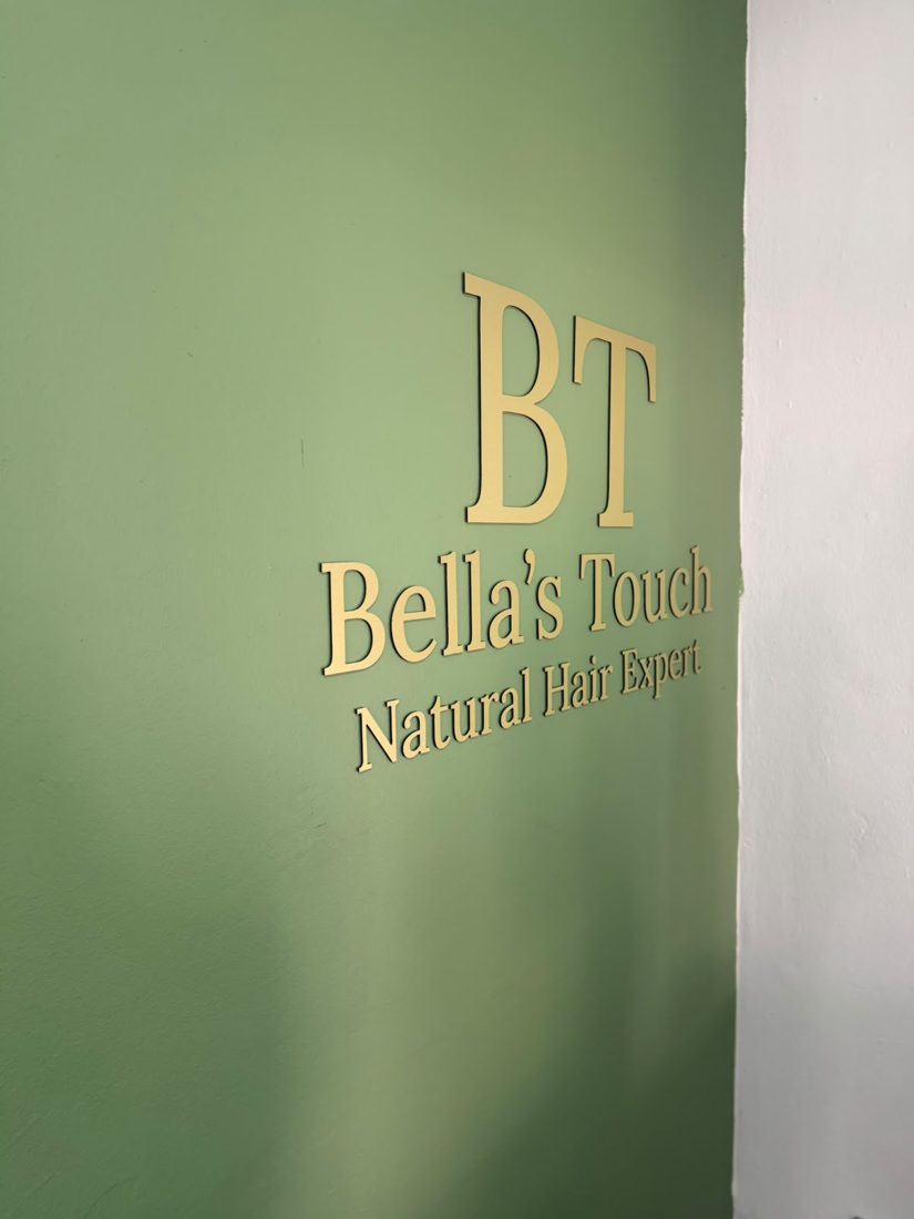 Close-up of the gold raised lettering, showing the letters standing off the wall