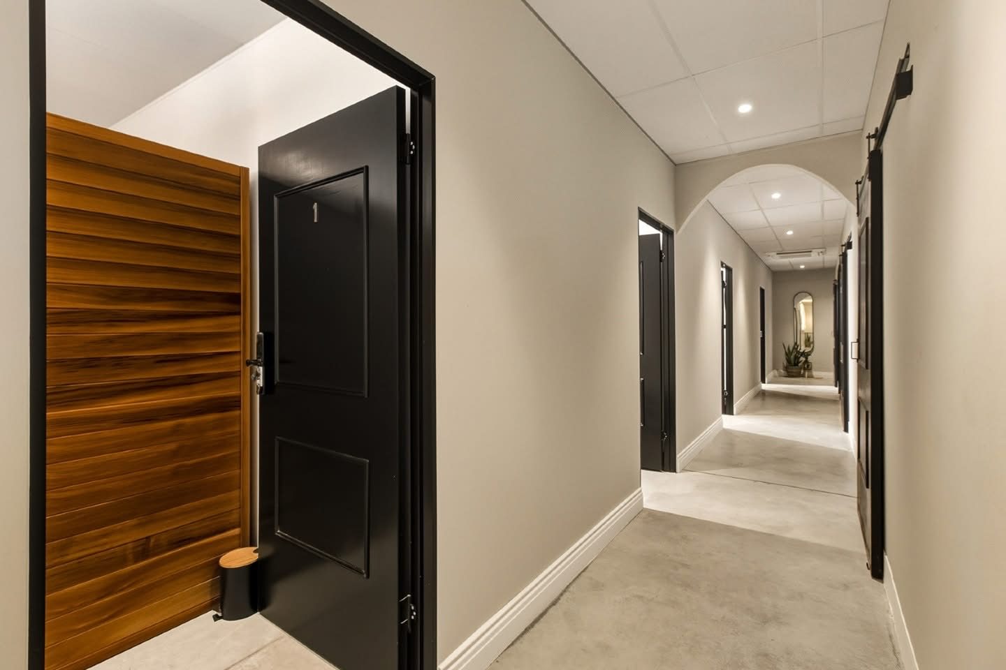 Corridor with black doors, suspended ceiling, downlights and an arched opening