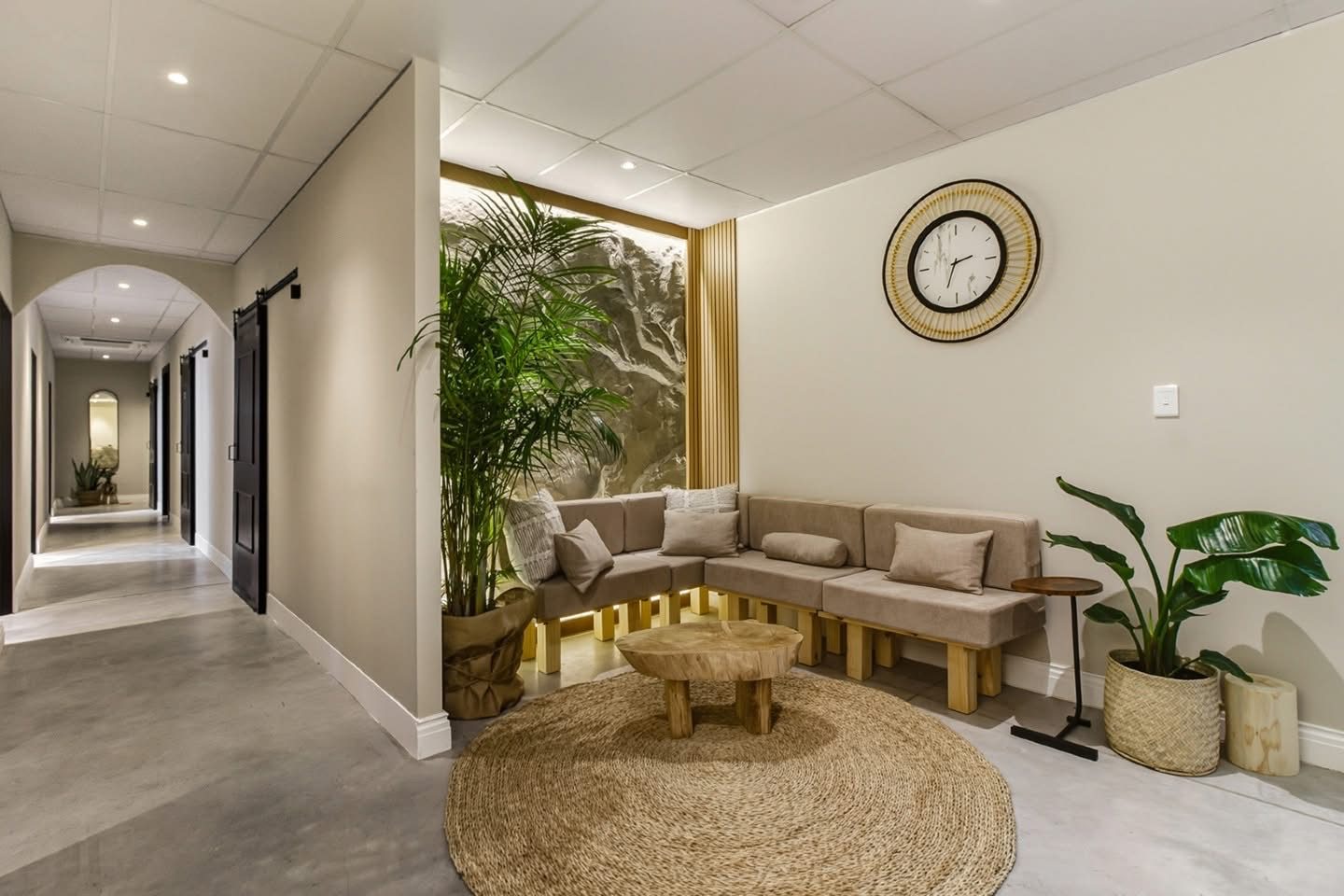 Lounge area with built-in timber seating, feature wall with lighting and arched corridor